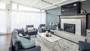 Ein modernes Wohnzimmer mit Kamin, bequemen Sitzmöglichkeiten und einem großen Fernseher.