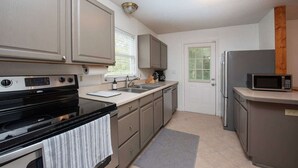 A compact kitchen with a stove, sink, and microwave.
