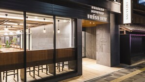 A modern interior with a long wooden table and chairs, a glass wall, and a sign reading "FRESSA INN".