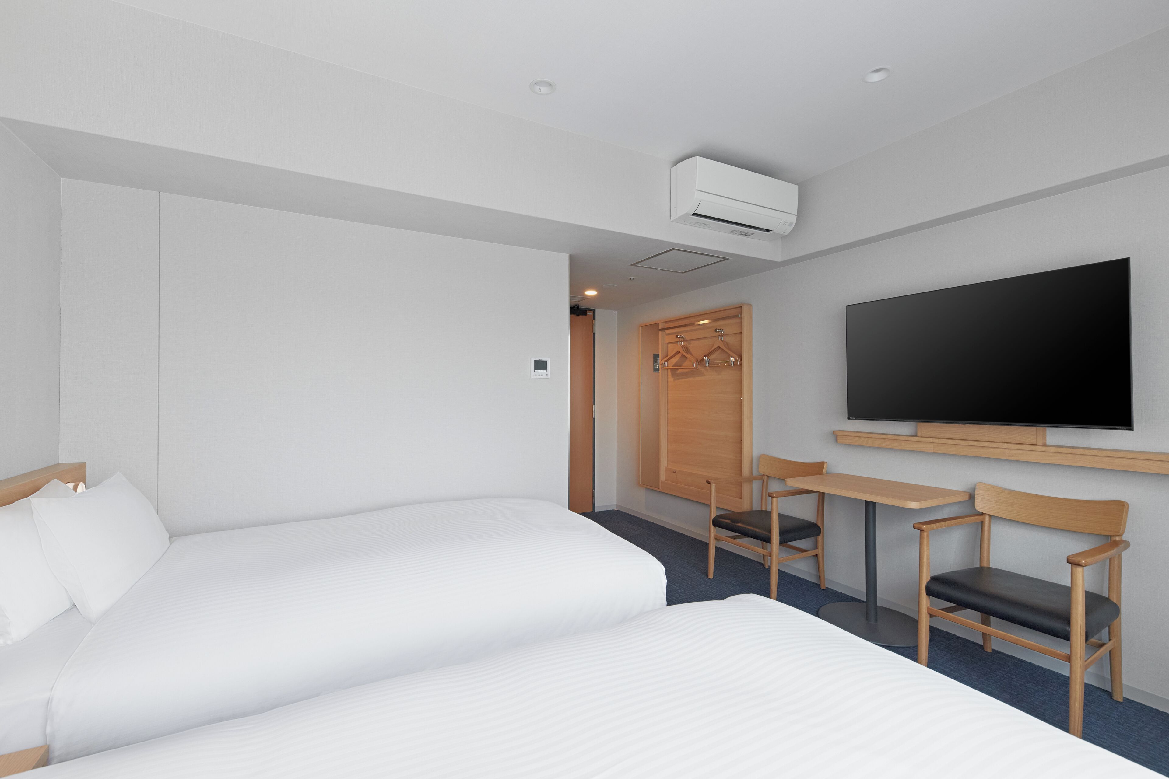 Habitación de hotel con dos camas, televisión, escritorio y una silla.