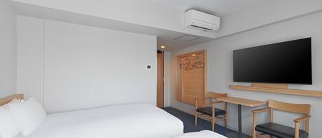 Quarto de hotel com duas camas, televisão, escrivaninha e uma cadeira.