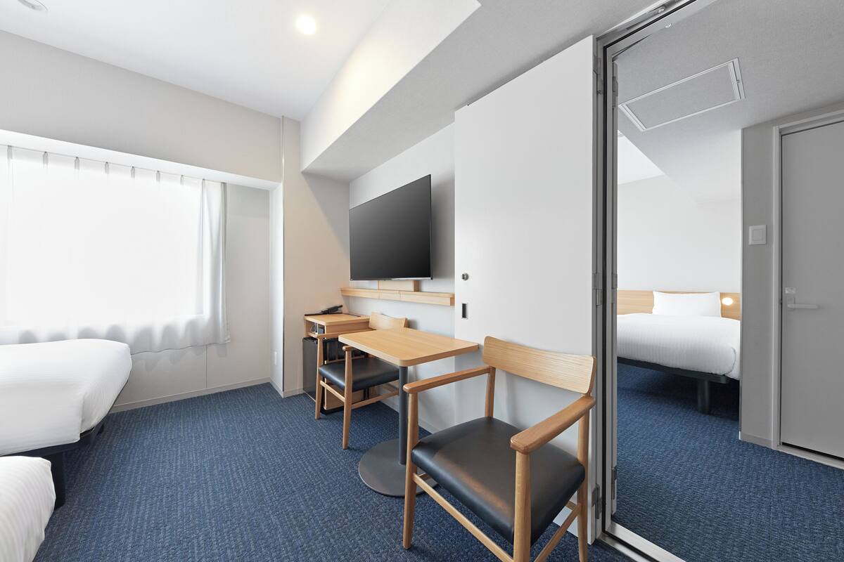 A hotel room with a bed, a desk, a chair, a television, and a sliding door.