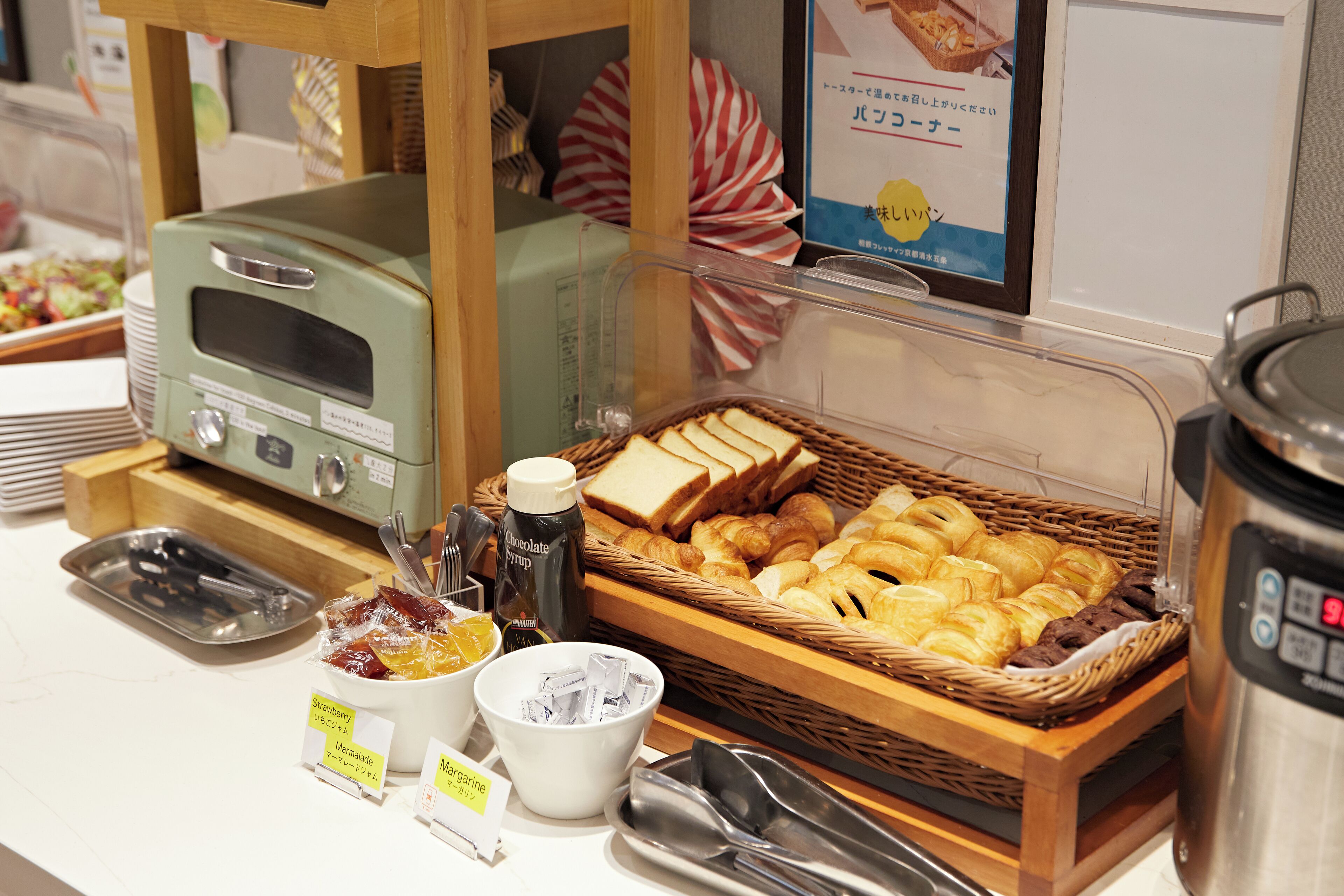 A breakfast buffet with bread, pastries, and condiments.