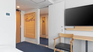 Een hotelkamer met een bed, een bureau, een stoel, een kledingkast en een televisie.