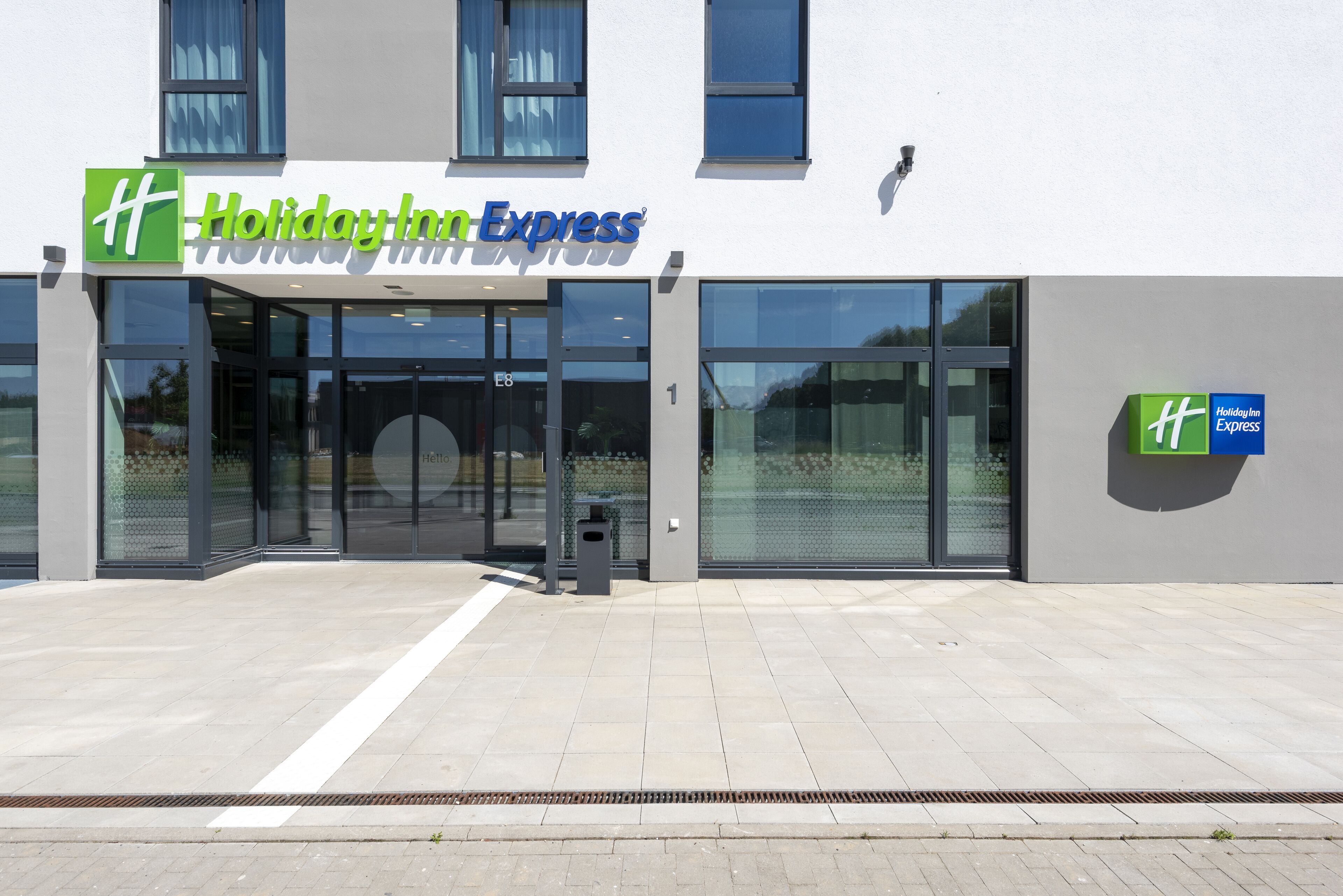 A Holiday Inn Express hotel with a modern facade, large glass windows, and a clean, tiled entrance area.