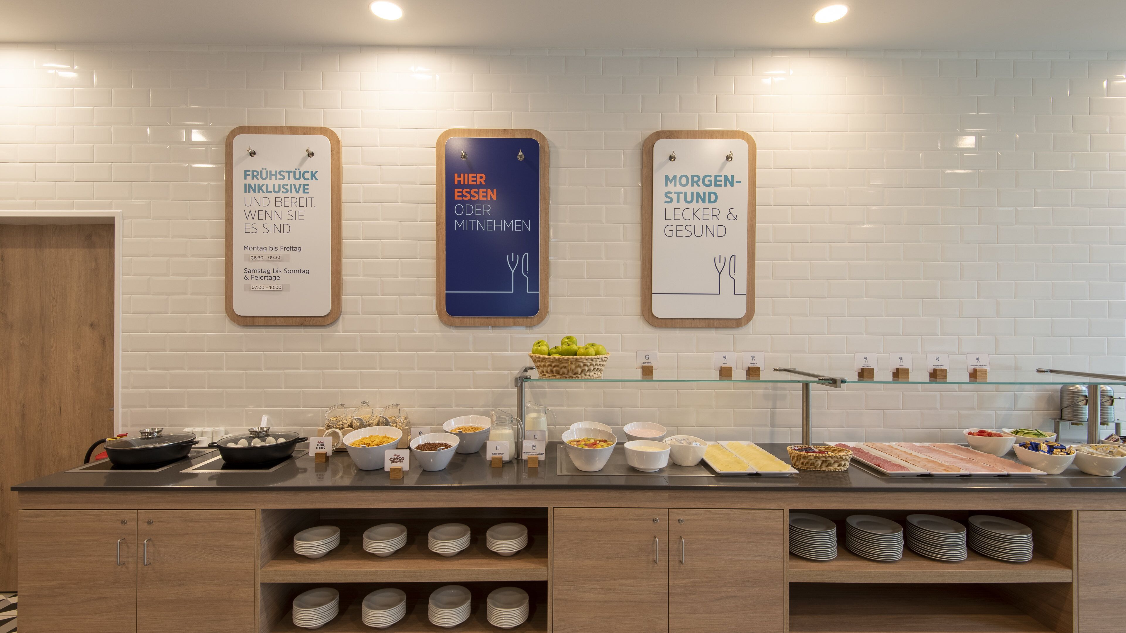 A breakfast buffet area with labeled serving times and a variety of food options.