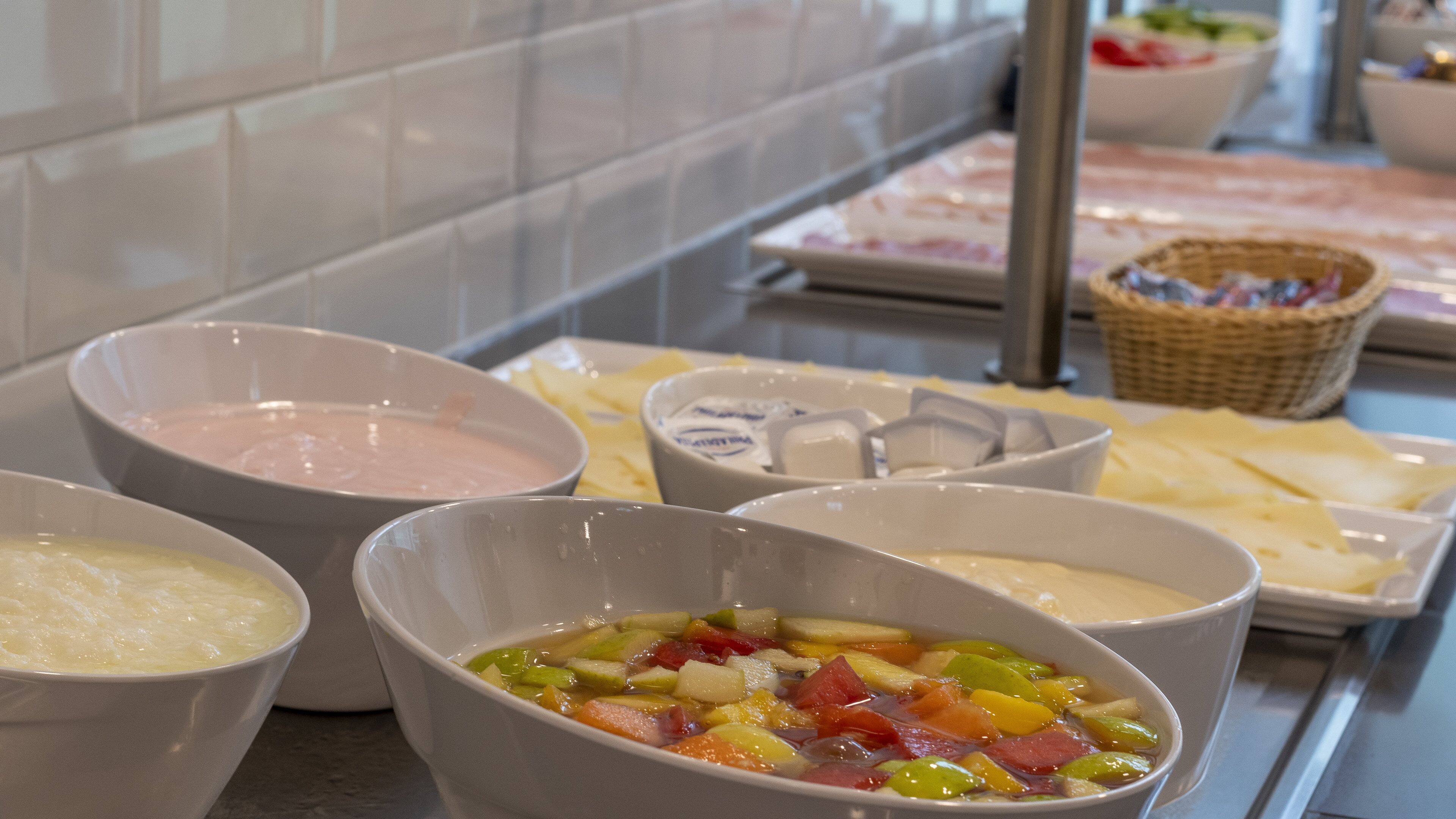 A buffet with various dishes including a fruit salad, a creamy soup, and a pink sauce.