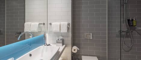A bathroom with a blue vanity sink, white toilet, and a shower area.