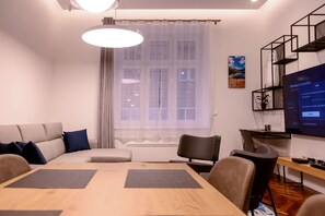 Una sala de estar moderna con una mesa de comedor de madera, un sofá y un televisor que muestra una pantalla de conexión inalámbrica.