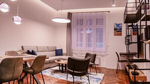 Un salon moderne comprenant un canapé, une table à manger, des chaises et un escalier.
