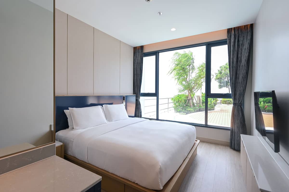 Ein modernes Hotelzimmer mit einem großen Bett, einem Flachbildfernseher und Blick ins Freie.