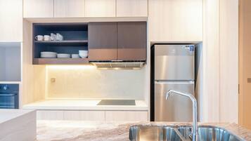 A modern kitchen with a stainless steel refrigerator, a built-in oven, and a marble countertop.