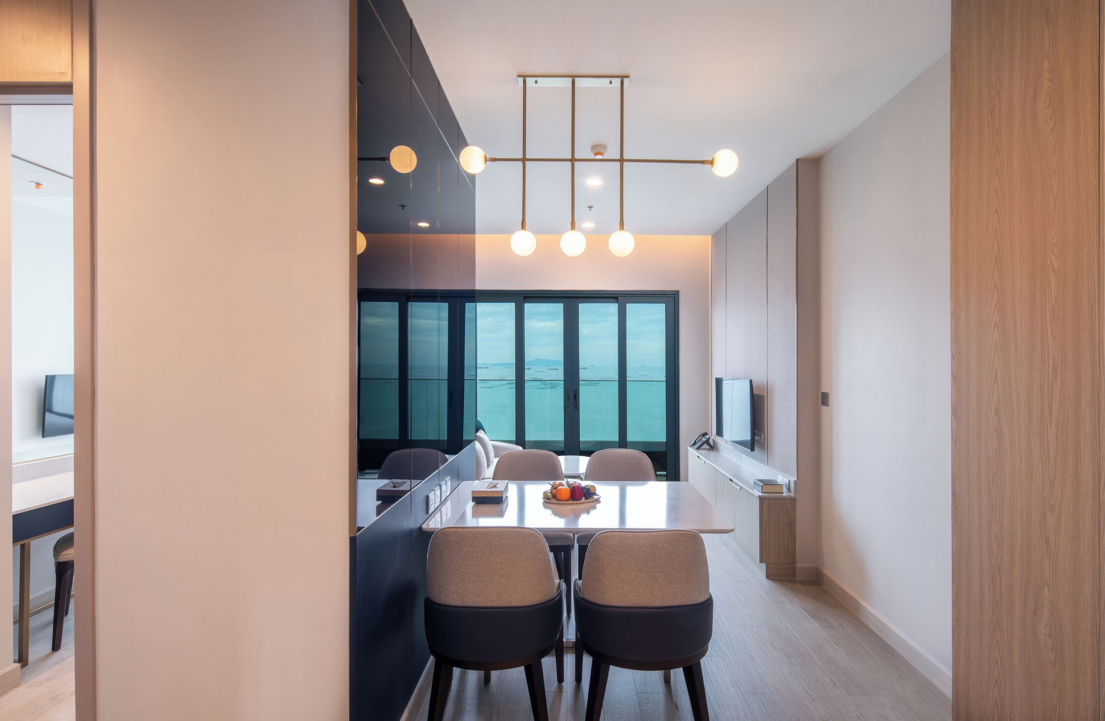 A modern kitchen with a central island, large windows, and a dining area with chairs.