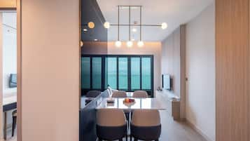 A modern kitchen with a central island, large windows, and a dining area with chairs.