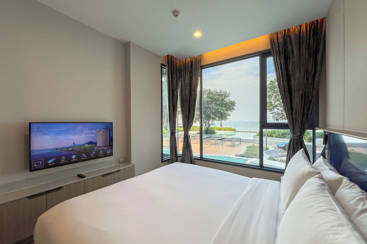 Ein Hotelzimmer mit einem Bett, einem Fernseher an der Wand und einem großen Fenster mit Vorhängen.