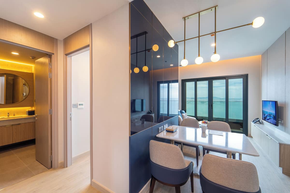 Ein modernes Hotelzimmer mit Essbereich, einem großen Fenster und einem Fernseher.