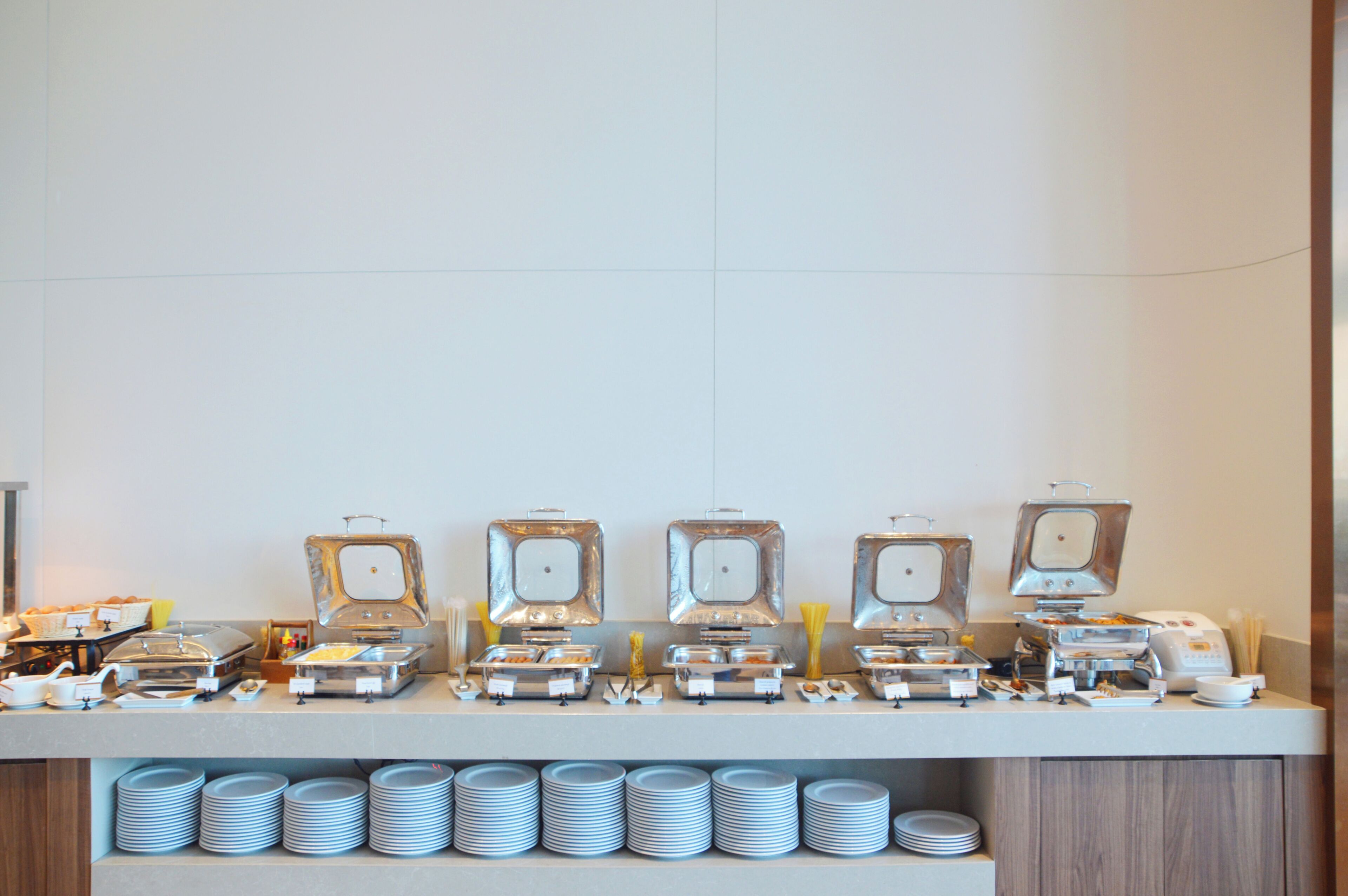 A buffet setup with multiple food stations and stacked plates.