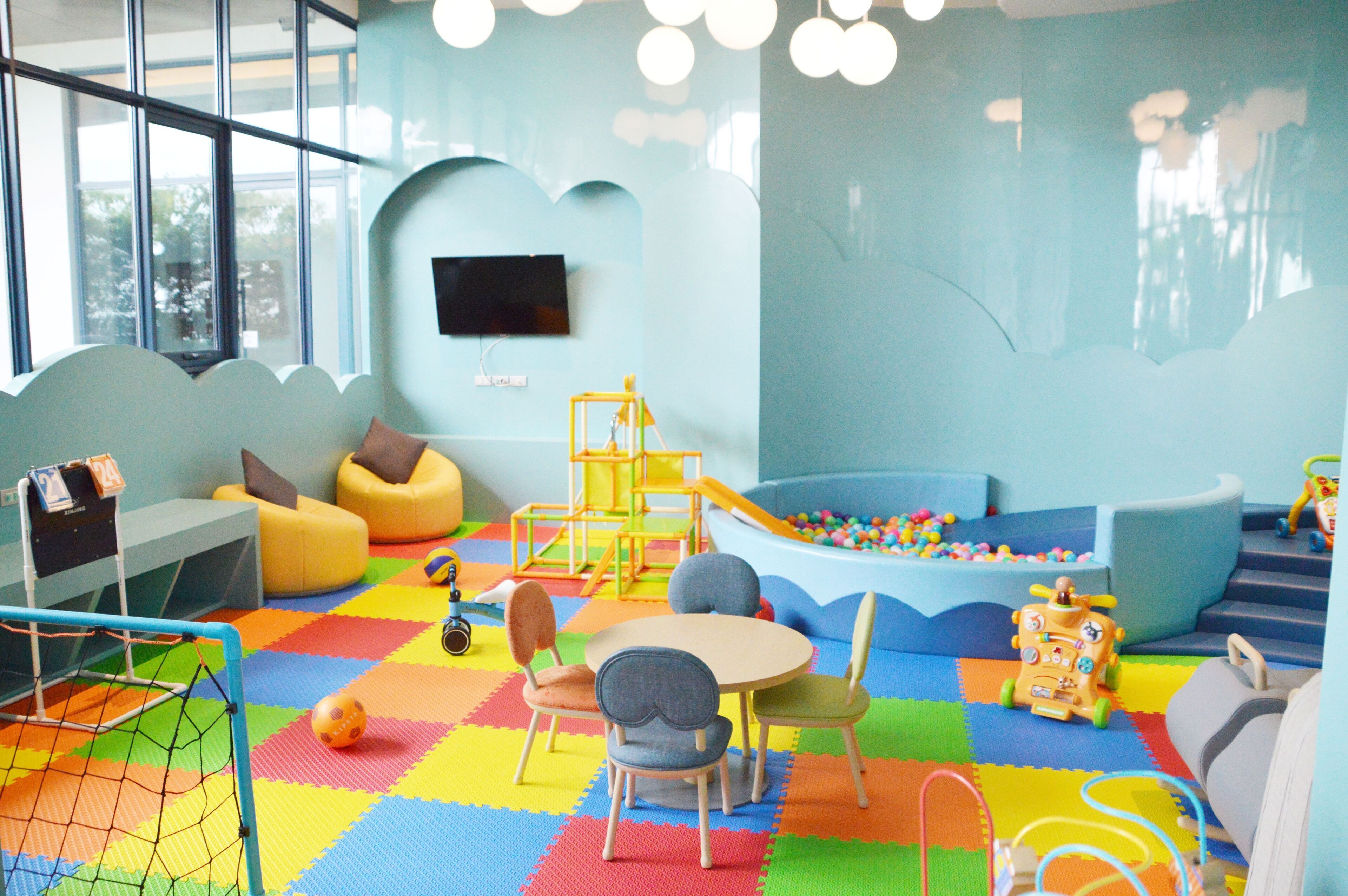 Un'area giochi per bambini con pavimento colorato, posti a sedere e strutture ludiche.
