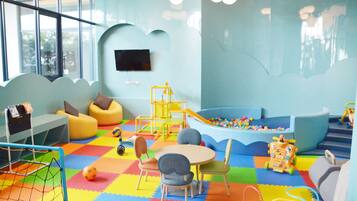 Un'area giochi per bambini con pavimento colorato, posti a sedere e strutture ludiche.