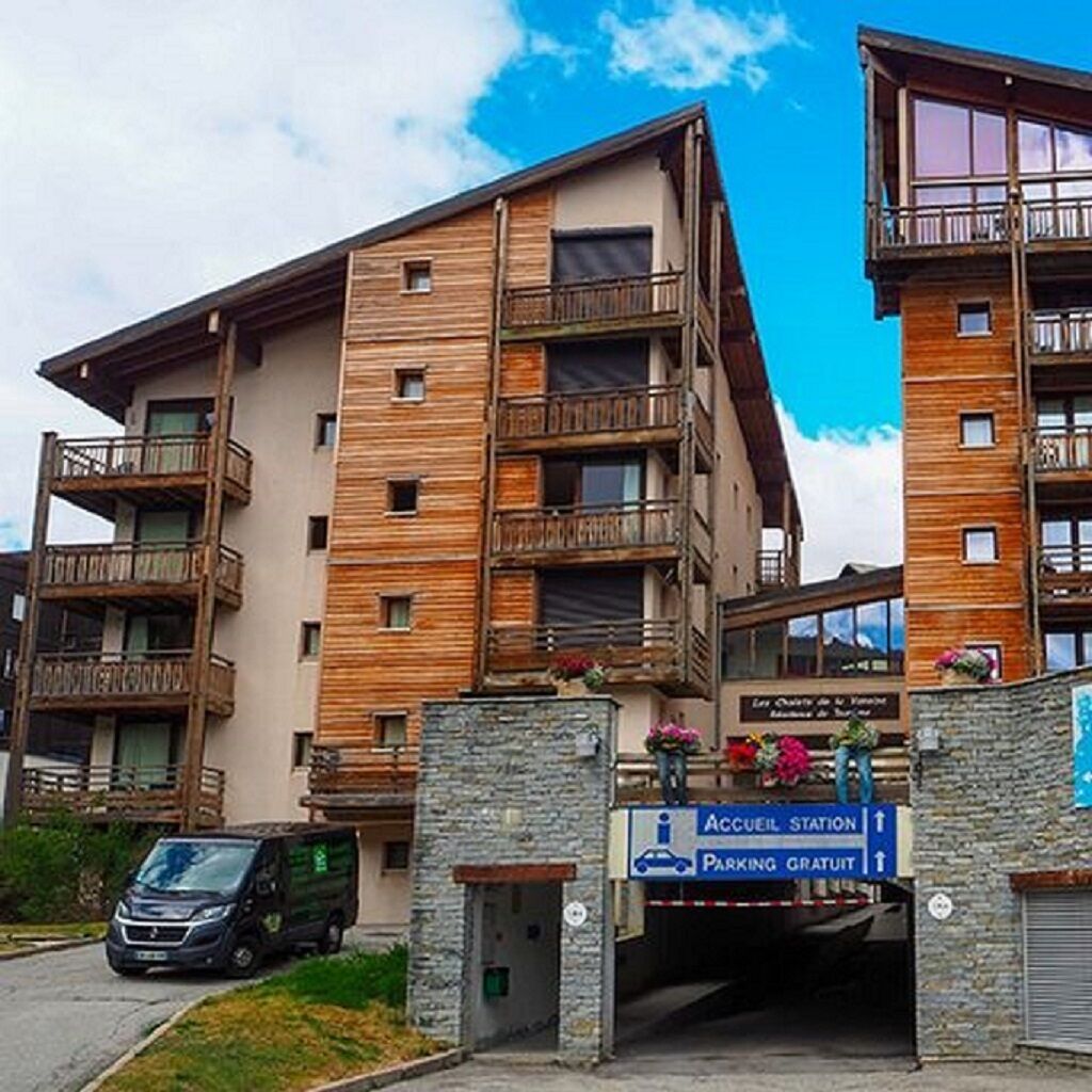 Ett hotell med flera våningar, balkonger, en parkeringsskylt och en entré av sten.