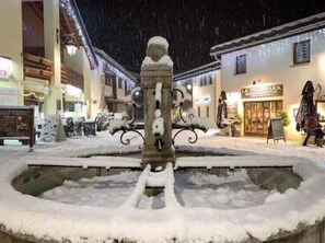 A snow-covered fountain in a town square with buildings in the background. - 🏔️ Enjoy a cozy mountain nest with an exceptional view! 🏔️ (La Norma)