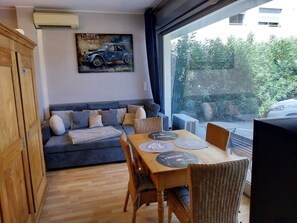 Una stanza con un divano, un tavolo da pranzo, sedie, un quadro e vista dalla finestra.