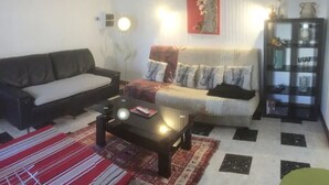 A living room with a sofa, a coffee table, a rug, and a cabinet with decorative items. - F2 apartment near Amélie les bains (Arles-sur-Tech)