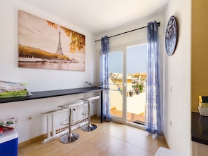 Una cocina moderna con encimera negra, radiador blanco y un cuadro de la Torre Eiffel.