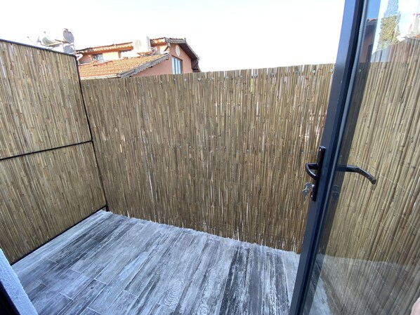 Um quarto com cerca de bambu, porta de vidro e chão ladrilhado.