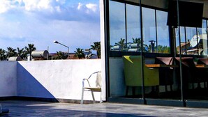 A modern building with a glass facade, a red roof, and a clear sky with clouds. - Nefis Hotel City (Fethiye)
