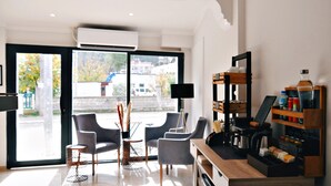A modern living room with a large sliding glass door leading to an outdoor area, a wooden coffee table, and a built-in bookshelf with various items. - Nefis Hotel City (Fethiye)
