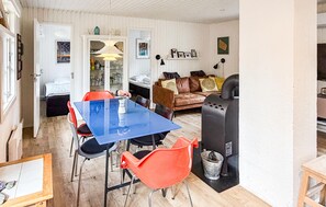 Une pièce avec une table bleue, des chaises rouges, un canapé marron et un barbecue noir.
