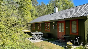 Eine kleine Hütte mit Ziegeldach, roter Tür und einem Fenster mit der Aufschrift '20' an der Wand.