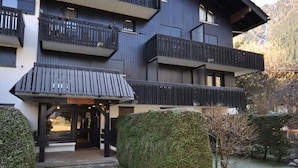 Un immeuble à plusieurs étages doté de balcons, d’une entrée couverte et d’un chemin de pierre menant à l’entrée.