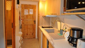 Une cuisine compacte avec des meubles en bois, un four à micro-ondes encastré, un évier et une machine à café.