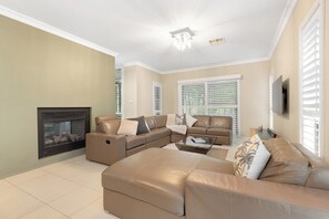 A living room with a sectional sofa, a fireplace, and a television mounted on the wall. - FAIRWAY & VINES - THE VINTAGE HOLIDAY HOUSES (Rothbury)