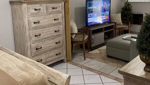 Una sala de estar con televisión, mueble de madera y ventana.