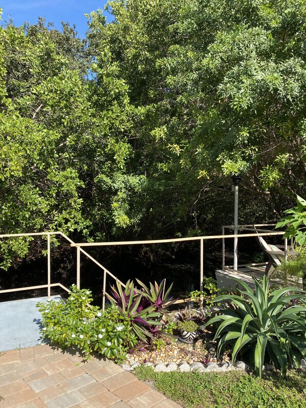 A garden with a wooden deck, potted plants, and a stone pathway.