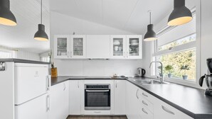 A modern kitchen with white cabinets, a built-in oven, a sink, and pendant lighting. - Amazing home in Nexø with WiFi (Nexø)