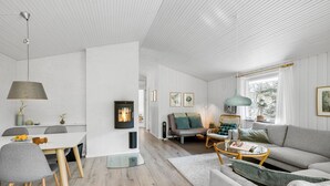 A modern living room with a fireplace, a dining area with a white table, and a sofa with a view of the outdoors. - Amazing home in Nexø with WiFi (Nexø)