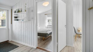 A modern bedroom with a bed, a bedside table, and a chair. There is a door leading to another room. - Amazing home in Nexø with WiFi (Nexø)