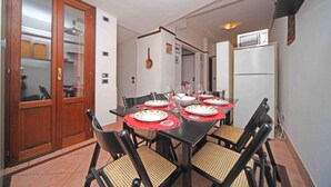 A dining area with a table set for four, chairs, a refrigerator, and a microwave. - Ca' Frutariol Apartment (Venezia)