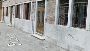 A row of buildings with uniform windows and doors, a paved street, and a sign indicating a location. - Ca' Frutariol Apartment (Venezia)