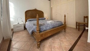 A bedroom with a four-poster bed, a nightstand, a chair, and a wardrobe. - Ca' Frutariol Apartment (Venezia)