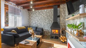 A cozy living room with a stone wall, a fireplace, a sofa, and a coffee table. - Amazing home in Perusic with sauna (Perusic)