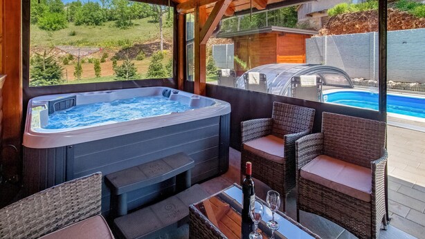 A hot tub area with wicker furniture and a view of a swimming pool. - Amazing home in Perusic with sauna (Perusic)