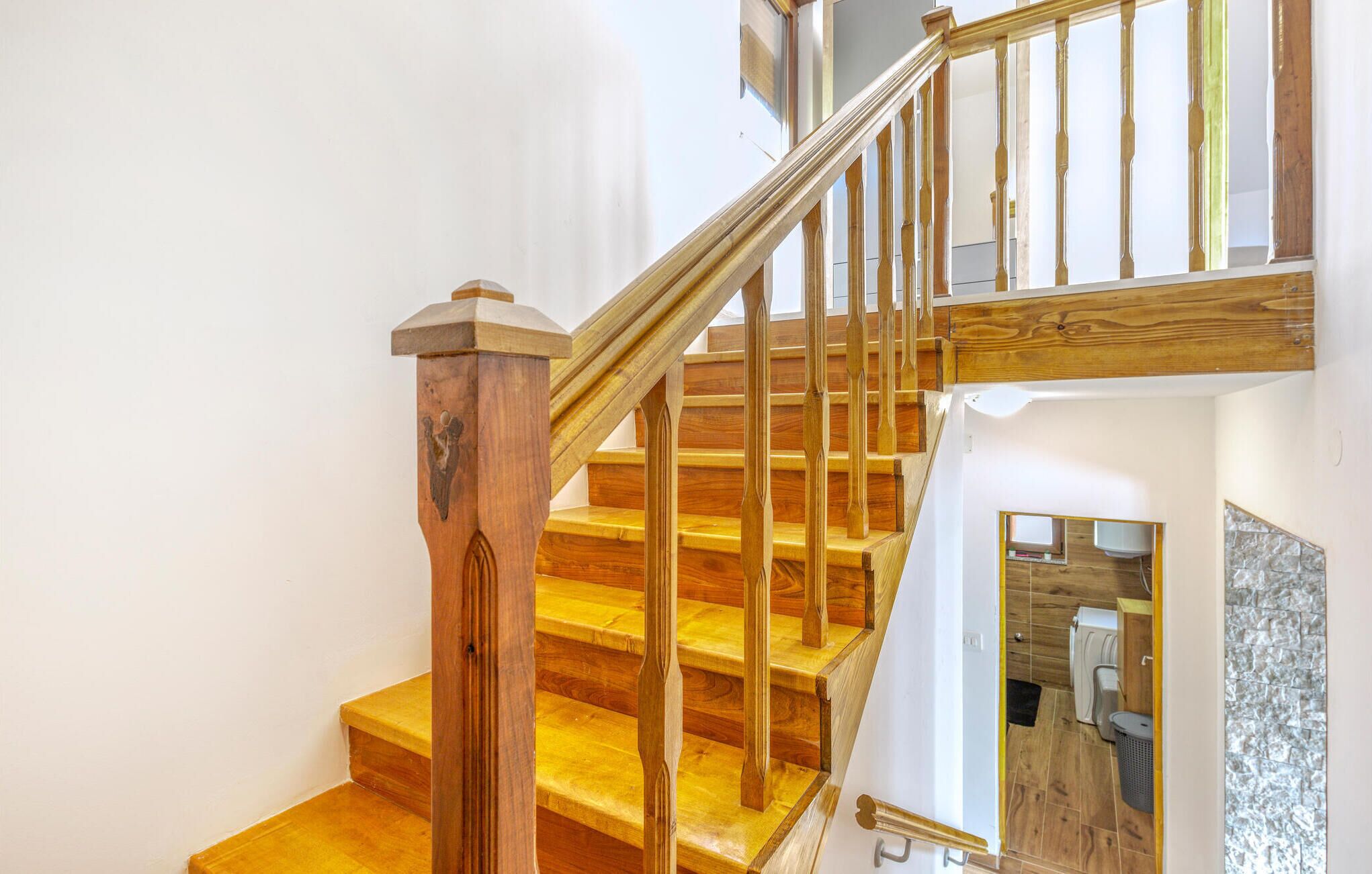 A wooden staircase with a handrail and a small decorative post.