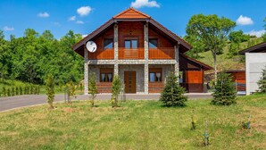 A two-story wooden house with a stone facade, a balcony, and a clock on the front. - Amazing home in Perusic with sauna (Perusic)