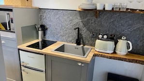 Een kleine keuken met een ingebouwde magnetron, een spoelbak en een koffiezetapparaat.