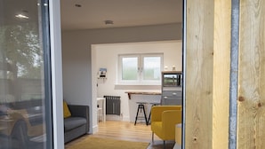 Een moderne woonkamer met een bank, een gele fauteuil en een salontafel.